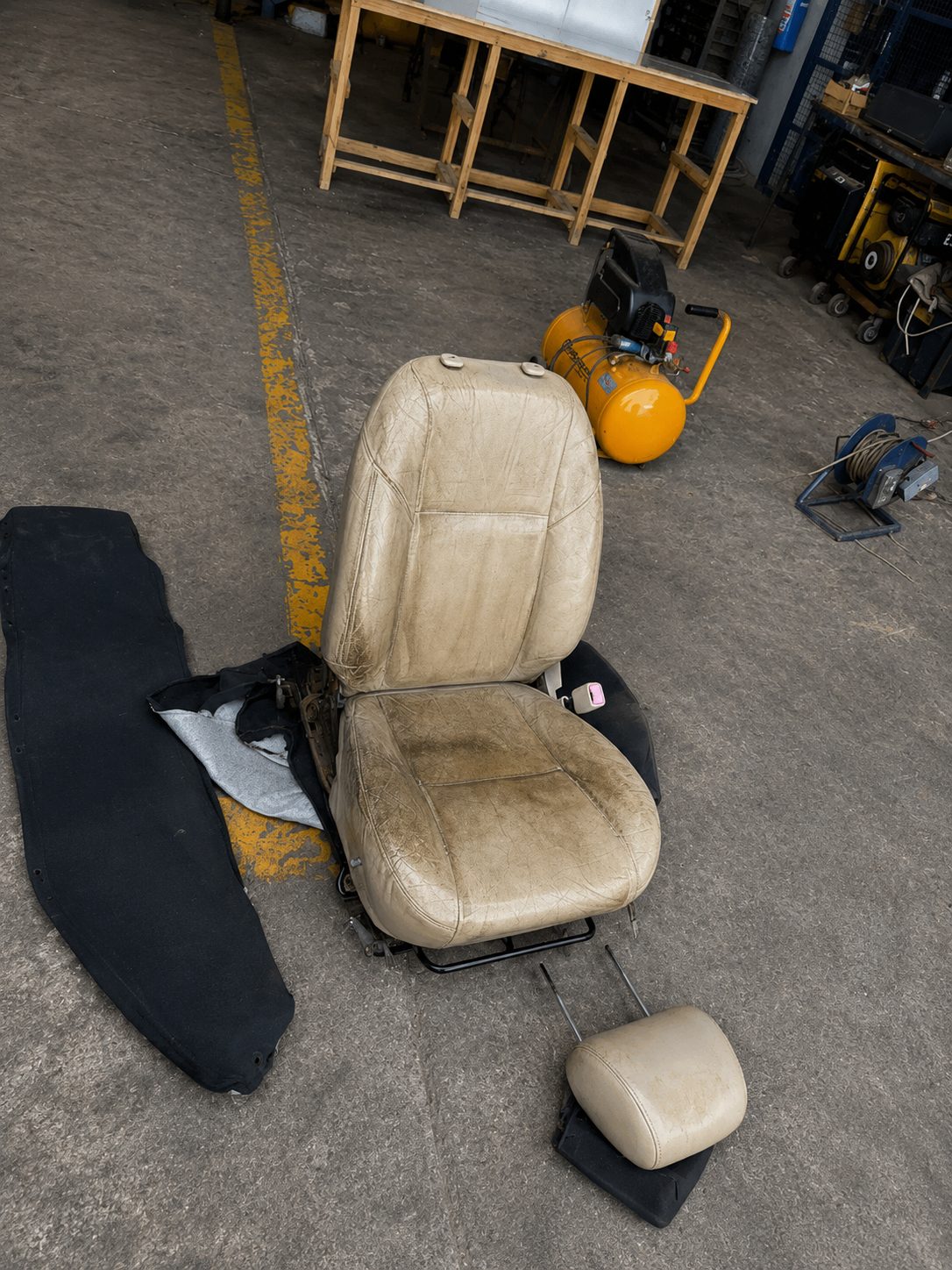 Faded and cracked tan leather seat stripped out for rebuild